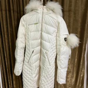 Vit dunjacka Rockandblue med pälskrage - Snygg vit dunjacka från Rockandblue med fluffig pälskrage och detaljer i silver. Jackan har quiltade partier, dragkedjor på fickor och ärm samt Rockandblue-logga på ärmen. Perfekt för kalla vinterdagar och ger en riktigt clean look.