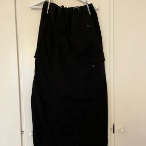 Svart cargokjol med fickor från Zara - Svart långkjol  i cargostil från Zara med elastisk midja och stora cargofickor på sidorna. 