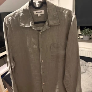 Beige linneskjorta från Kappahl - Snygg beige skjorta från Kappahl i luftig linnemix. Klassisk krage, bröstficka och knäppning framtill. Perfekt för en chill och stilren look, passar till både jeans och shorts. Långärmad och med avslappnad passform.