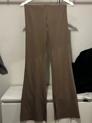 Bruna vida leggings i mjukt material - Snygga bruna leggings med vida ben och hög midja. Tillverkade i ett mjukt och stretchigt material som sitter skönt på kroppen. Perfekta för dig som gillar en relaxed och trendig stil.