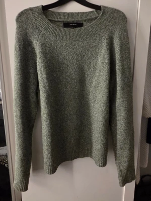 Gråmelerad stickad tröja VERA MODA - Mysig gråmelerad stickad tröja från VERA MODA med rund halsringning och ribbade muddar vid ärmslut och nederkant. Perfekt för kyliga dagar och enkel att matcha med olika outfits. Materialet känns mjukt och behagligt mot huden.