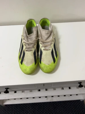 Adidas Predator fotbollsskor gul/svart - Adidas Predator fotbollsskor med klassiska svarta ränder och en fräsch gul färg framtill. Skorna har snörning och är tillverkade i syntetmaterial för bästa grepp och känsla på planen. Perfekta för dig som vill sticka ut på fotbollsplanen.