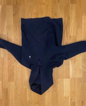 Ralph Lauren hoodie  - En blå Ralph Lauren hoodie med vit loga i storlek junior large , den är lite solblekt men annars i bra skick . Använt ganska lite . Skick skulle jag säga 7/10 .  BILDERNA BLEV UPP OCH NER 