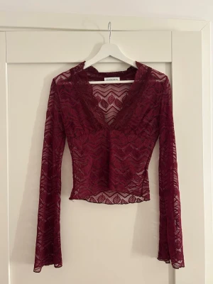Vinröd spetsblus från Venderbys - Vinröd långärmad spetsblus från Venderbys med v-ringning och transparent mönster. Bara använd en gång! Lappen säger storlek S/M men tycker den är mer åt S hållet. 