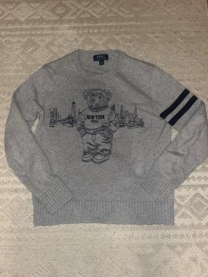 Ralph Lauren Polo Bear grå stickad tröja - Säljer denna Feta Ralph Lauren Polo Björn tröja som är grå. Den är i storlek 14-16 som motsvarar XS. Den är perfekt för kall väder och den har inga defekter eller tecken på användning. Original Pris 1200kr.
