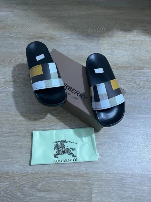  sandaler med rutigt mönster - Snygga sandaler  med klassiskt rutigt mönster i svart, vitt, gult och beige. Tillverkade i syntetmaterial med präglad  på sidan. Perfekta för sommaren och ger en lyxig touch till din outfit.