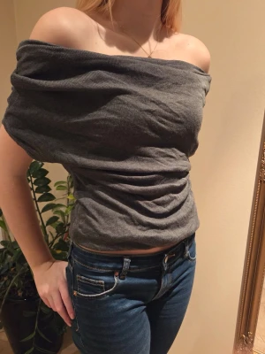 Grå offshoulder topp i ribbad  - Trendig grå offshoulder topp i ribbad bomull. Sitter snyggt och har en croppad passform som framhäver axlarna. Perfekt för dig som vill ha en stilren och modern look.