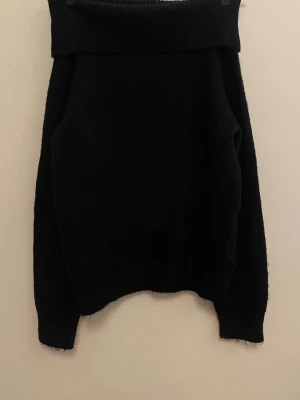 Svart off shoulder stickad tröja - Superfin svart stickad tröja med bred off shoulder-krage. Tröjan har ribbstickade muddar vid ärmslut och nederkant. Ifrån H&M, strl 146/152, endast använd någon gång💗 Innehåller även någon sorts ull. Kan skicka flera bilder samt diskutera pris! 