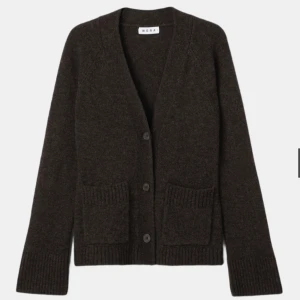 Mörkbrun kofta från Wera - Kofta i mjuk mörkbrun ullmix från Wera. Modellen har v-ringning, stora knappar framtill och två rymliga fickor. Ribbstickade muddar vid ärmslut och nederkant ger en snygg detalj. Perfekt för lager på lager och en chill look.