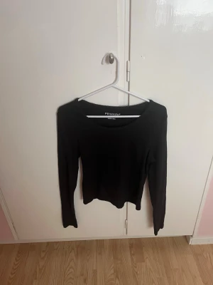 Långärmad tröja  - En enkel och stilren svart långärmad topp från Primark. Modellen har rund halsringning och är tillverkad i ett mjukt, stretchigt material som sitter skönt på kroppen. Perfekt basplagg att matcha med olika outfits.