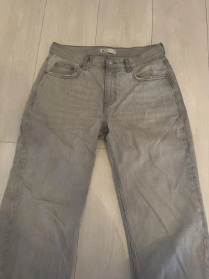 Gråa lågmidjade jeans från Gina Tricot - Snygga grå jeans från Gina Tricot i klassisk femficksmodell. Jeansen har rak passform och låg/normal midja, perfekta till en avslappnad stil. Tillverkade i mjukt bomullsmaterial för skön känsla hela dagen.