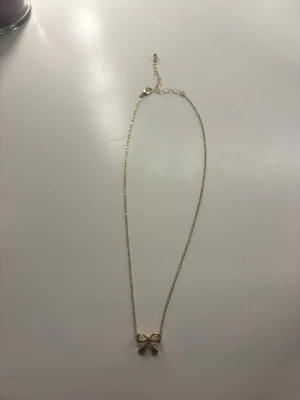 Guldhalsband - Jättegulligt guldhalsband med en liten rosett. Passar till alla outfits! Minns tyvärr inte vart jag köpt den  