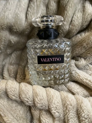 Valentino parfym i kristallflaska - Säljer en lyxig parfym från Valentino i en transparent, kristallmönstrad glasflaska med svart och silverfärgad detalj vid halsen. Flaskan har en elegant, multifacetterad kork och en svart etikett med rosa text. Perfekt för dig som gillar exklusiva dofter och snygg design.