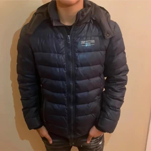 Svart Replay Jacka - Snygg och varm svart dunjacka från Replay med huva och dragkedja. Perfekt för kyliga dagar med sin design. Jackan har en stilren look, billigare snabb affär!