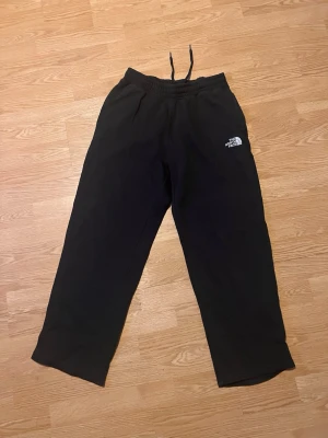 Svarta mjukisbyxor från The North Face - Svarta mjukisbyxor från The North Face med broderad logga på vänster ben. Byxorna har resår i midjan med snörning och är tillverkade i mjukt bomullsmaterial. Perfekta för chill eller träning, loose fit och klassisk stil. Mycket bra skick, storlek S😊