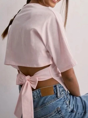 Nelly bow T-shirt  - Säljer min Nellys fina T-shirt med en stor rosett man knyter i ryggen! Nyskick, har använt fåtal gånger ⭐️💘