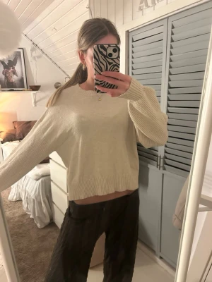 Beige  stickad tröja - Beige stickad tröja med rund halsringning. Tröjan har breda ribbade muddar vid ärmslut och nederkant. Perfekt för lager-på-lager och enkel att matcha med olika stilar. Defekter syns på bild