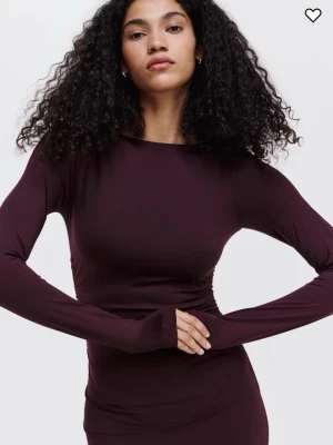 Vinröd klänning H&M, DM för bilder - Snygg mörkbrun klänning med lång ärm och figurnära passform. Klänningen har rund halsringning och är tillverkad i ett stretchigt material som sitter tight mot kroppen. Perfekt för dig som gillar en stilren och elegant look.
