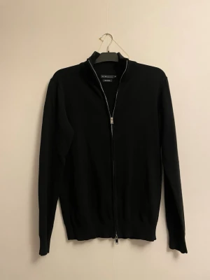 Svart ziptröja  - Snygg svart ziptröja från Oscar Jacobson med hel dragkedja och ribbade muddar. Tröjan har hög krage och är tillverkad i mjukt stickat material. Perfekt för en clean och stilren look. Flera bilder går o ordna hör av er via intresse mvh Top seller 