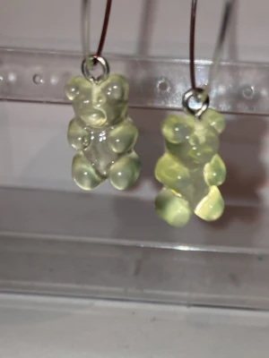 Örhängen med genomskinliga nallebjörnar - Säljer ett par handgjorda örhängen med genomskinliga nallebjörnsberlocker i plast. Hängena har en söt och lekfull design som sticker ut. Perfekta för dig som gillar unika accessoarer med en rolig twist.