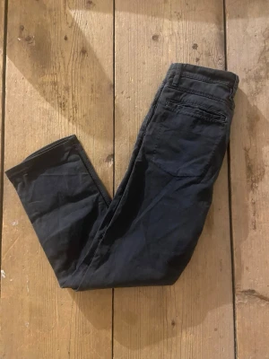 Svarta byxor från Nudie Jeans, W29 L34 - Säljer ett par svarta byxor från Nudie Jeans i storlek W29 L34. Byxorna har klassisk rak passform med fem fickor och bälteshällor. Materialet är mjukt och känns som bomull, perfekta till en chill och stilren look.