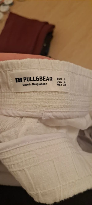 Vita linnebyxor från Pull&Bear L - Snygga vita linnebyxor från Pull&Bear i storlek L. Byxorna har rak passform, elastisk midja med snörning och praktiska fickor både fram och bak. Perfekta för chill dagar och sommarhäng. Luftigt material som känns skönt mot huden.