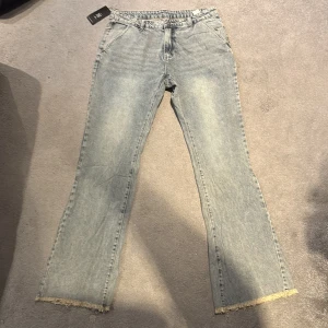 Ljusblåa flared jeans Sumwon - Snygga ljusblå/grå jeans från Sumwon med flared-modell och rå, fransad kant längst ner på benen. Jeansen har klassiska fickor fram och bak sammt bälteshällor.
