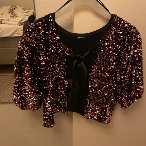 Bolerotopp från Gina med paljetter - Säljer nu denna festliga bolerotopp i storlek S. Tröjan är oanvänd och i nyskick<3<3 Perfekt för att sticka ut med extra glam på fest!