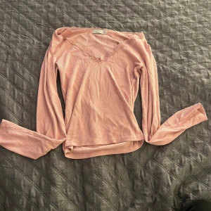 Rosa ribbad långärmad topp Stradivarius - Säljer en ljusrosa långärmad topp från Stradivarius i storlek S. Toppen har ribbad struktur, v-ringad hals med spetsdetalj och är figurnära i modellen. Perfekt för dig som gillar mjuka färger och snygga detaljer.