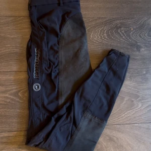Pikeur ridbyxor  - Helskodda marinblå ridbyxor ifrån Pikeur. Modellen heter Lucinda, medelhög midja med mockaliknande material i skoningen. Ljusblå logga på vänster ben. Storlek 34, passar mig som har S/M normalt.  Använda men fint skick! Noppriga i sitsen (syns på bild) men annars inga defekter, sömmarna är fina och inga hål 