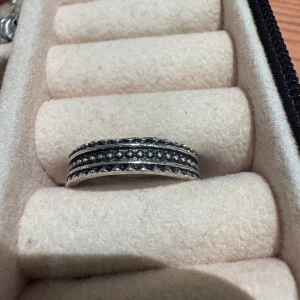 Silverfärgad ring med pärldetaljer - Cool ring i silverfärg med tre rader av små pärldetaljer och vågig kant. Ringen har en bred design som sticker ut och passar perfekt om du gillar smycken med lite edge. Snygg att kombinera med andra ringar eller bära ensam för en statement-look.