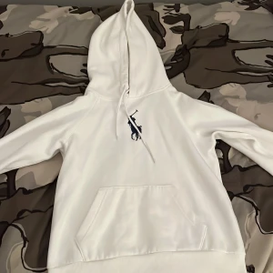 Vit hoodie från Polo Ralph Lauren XS - Vit hoodie från Polo Ralph Lauren i storlek XS. Klassisk design med stor blå logga på bröstet, huva med snörning och magficka. Använd väldigt få gånger, ny pris ca 2100kr priset är ej hugget i sten