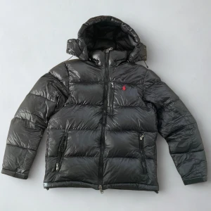 Polo Ralph Lauren Jacka - Säljer min polo Ralph lauren jacka. Svart och glansig (Dunjacka). Jag tog bort karborre banden på armarna då jag tyckte det va fult. Det finns ett liiitet hål-märke, men inget man tänker på. (Sida 5). Annars är det jättefin, hör av dig vid frågor och intresse. Lägg ett prisförslag eller byt mot något!👍