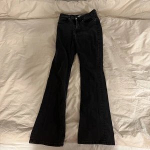 Svarta bootcut jeans från H&M - Svarta jeans från H&M med klassisk femficksdesign och dragkedja fram. Modellen har bootcut-ben som ger en snygg siluett och är tillverkade i mjukt jeanstyg. Perfekt för dig som gillar en retro vibe och vill ha ett par jeans med lite extra attityd.