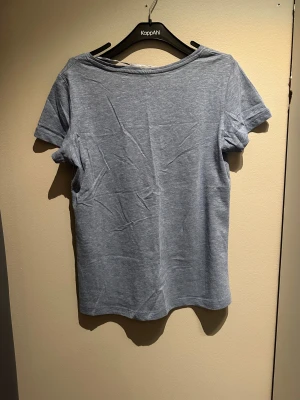 Ljusblå v-ringad t-shirt KappAhl - Snygg ljusblå t-shirt från KappAhl i storlek S. Modellen har v-ringad hals och korta ärmar, 