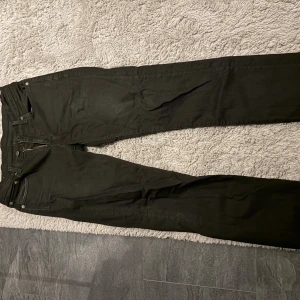 Svarta Levi's 514 jeans W30 L32 - Svarta jeans från Levi's modell 514 med klassisk femficksdesign och rak passform. Jeansen har dragkedja i gylfen och detaljer i silverfärgad metall. Materialet är slitstarkt denim och färgen är helsvart, perfekt för en clean och stilren look.