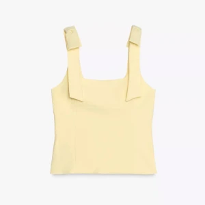 Ljusgul linnetopp med rosettband - Superfin ljusgul linnetopp med breda axelband som avslutas med snygga rosettliknande detaljer. Toppen har en rak och croppad passform med fyrkantig halsringning. Perfekt för sommarens alla tillfällen och ger en fräsch vibe till din outfit.