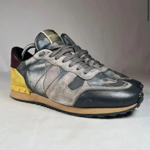 Valentino Rockrunner sneakers camo - Snygga Valentino Rockrunner sneakers med grått och svart camouflage-mönster, gul mockadetalj på hälen och vinröd skinnpanel. Sulan är 27,5cm