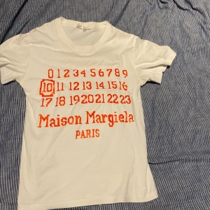 Maison margiela tee - Skön maison marginella tröja som e vit med orange text som är tvär fet storlek /165