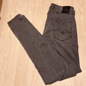 Replay Anbass grå jeans - Snygga Replay Anbass jeans i mörkgrå tvätt med klassisk femficksdesign och svarta detaljer på bakfickan. Slimmad passform och stretchigt material för skön känsla. Perfekt för dig som gillar stilrena och moderna jeans med en cool vibe. Storlek 29/32! Hör gärna av er vid frågor och skicka gärna prisförslag🙌🏼