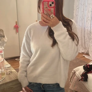 Vit fluffig stickad tröja H&M - Mysig vit stickad tröja från H&M i storlek M. Tröjan har en rund halsringning, långärmade ärmar och är gjord i ett supermjukt, fluffigt material som känns skönt mot huden. Perfekt för att hålla sig varm och ändå se chill ut.