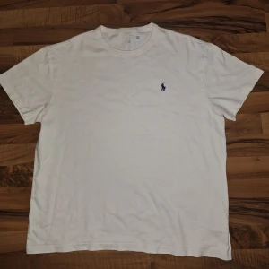 Vit t-shirt från Ralph Lauren - Vit t-shirt från Ralph Lauren med klassisk blå broderad logga på bröstet. T-shirten har rund hals, korta ärmar och är gjord i mjuk bomull. Enkel och stilren modell. Priset kan diskuteras 