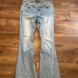True Religion Joey ljusblå flare jeans - Säljer ett par ljusblå Joey jeans från True Religion med låg midja och flare-ben. Snygga detaljer på baksidan! Har inte använt de så många gånger så de är nästan helt nya. Orginal kostar de 1300kr 💞
