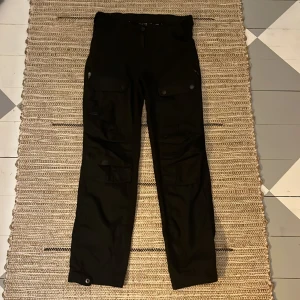 Five seasons vandrings byxor i svart. - Svarta vandrings byxor med knappar på botten för reglering. Byxorna har sex fickor.