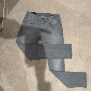 Grå jeansbyxor från Dondup  - Säljer ett par grå jeansbyxor från Dondup med klassisk femficksdesign och raka ben. Byxorna har diskreta sömmar och Dondup-logga på linningen bak. Materialet är mjukt denim i bomull med en snygg tvättad look. Dessa är i mycket bra skick och är i strl 31.