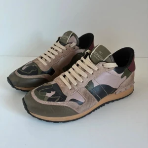 Valentino Rockrunner sneakers camouflage - Snygga Valentino Rockrunner sneakers med beige, gröna och svarta camouflage-detaljer. Skorna har mocka- och skinnpaneler, klassisk snörning och svart yttersula. Ikoniska nitar baktill och cool mix av material och färger gör dem till ett statement.  Inget og tillkommer 