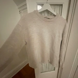 Beige tröja från Zara - En enkel och snygg beige stickad tröja från Zara med rundad hals och ribbad kant. Modellen är normal i passningen och har långa armar. Materialet är mjukt och skönt mot huden. Säljer pga liten användning! ❤️