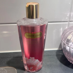 Victoria's Secret Sheer Love Body Wash - Victoria's Secret Sheer Love Body Wash med doft av white cotton och pink lily. Kommer i en genomskinlig plastflaska med rosa etikett och guldfärgat lock. Innehåller aloe vera och vitamin E. 