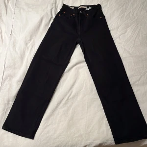 Levi's Ribcage Straight svarta jeans - Svarta Levi's Ribcage Straight jeans med klassisk femficksdesign och raka ben. Hög midja och snygga kopparfärgade nitar. Tillverkade i kraftig denim som ger en tidlös look. 