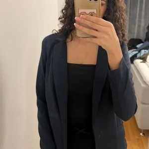 Marinblå kavaj - Helt oanvänd kavaj med fin feminin passform. Har inbyggda axlar, men get inte en för bred look. Den slutar undet höften. Inga defekter.